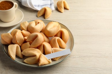 Photo of Tasty fortune cookies and paper with prediction on wooden table, space for text