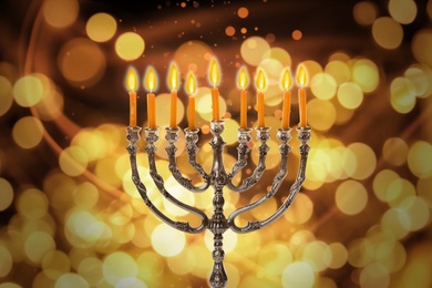 Silver menorah with burning candles against blurred lights. Hanukkah celebration
