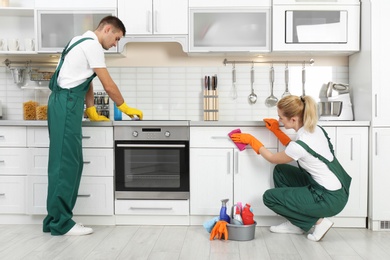 Team of janitors cleaning kitchen in house