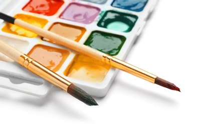 Brushes and plastic palette with colorful paints on white background