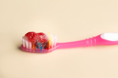 Photo of Toothbrush with paste and blood on beige background, closeup. Gum inflammation