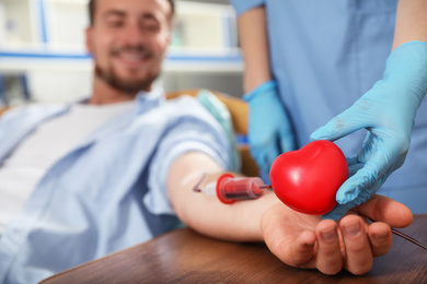 Photo of Young man making blood donation in hospital, focus on hands