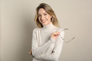 Portrait of happy young woman with beautiful blonde hair and charming smile on beige background
