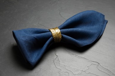 Blue fabric napkin with beautiful decorative ring on dark table
