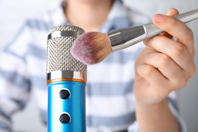 Woman making ASMR sounds with microphone and brush, closeup