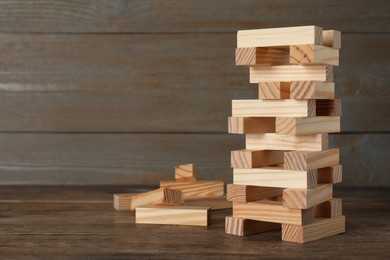 Jenga tower made of wooden blocks on table, space for text