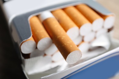 Cigarettes with orange filters in paper pack, closeup