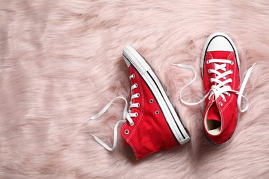 Photo of Pair of stylish red shoes on faux fur rug, flat lay. Space for text
