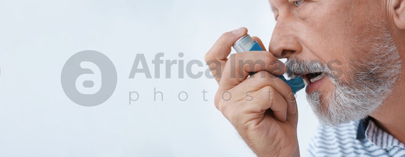 Image of Closeup view of man using asthma inhaler on white background, space for text. Banner design