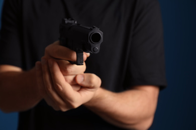 Man holding gun on dark background, closeup