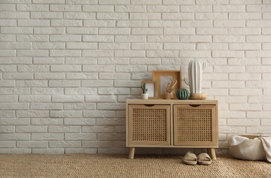 Stylish room interior with wooden cabinet near white brick wall. Space for text