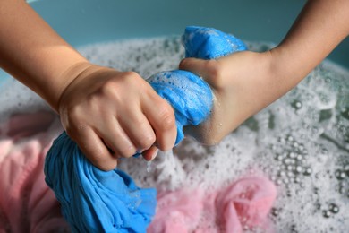 Photo of Woman wringing garment over basin, closeup. Hand washing laundry