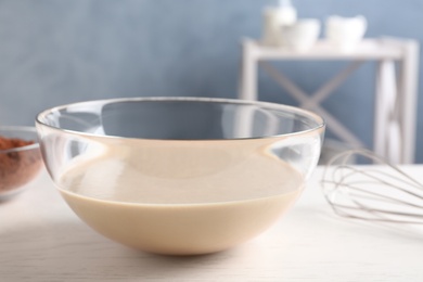 Glass bowl with batter on white table in kitchen