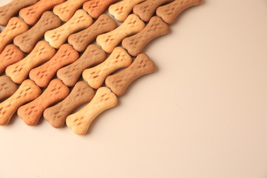 Photo of Bone shaped dog cookies on beige background, space for text