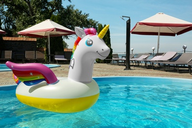 Funny inflatable unicorn ring floating in swimming pool on sunny day, outdoors. Space for text