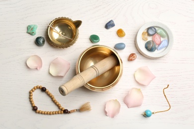 Flat lay composition with golden singing bowl on white wooden table. Sound healing