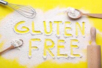 Kitchen utensils and phrase Gluten free written with flour on yellow background, flat lay