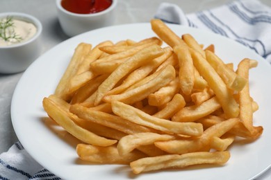 Photo of Tasty french fries served with ketchup and mayonnaise on grey marble table, closeup