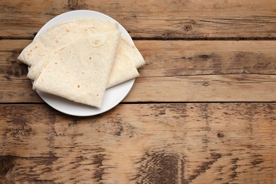 Photo of Delicious folded Armenian lavash on wooden table, top view. Space for text