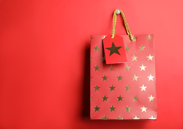 Shopping paper bag with star pattern on red background, space for text
