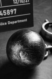 Metal ball with chain and mugshot letter board on grey table, closeup