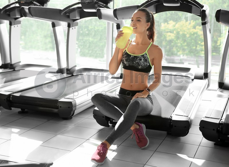 Portrait of athletic woman with protein shake in gym