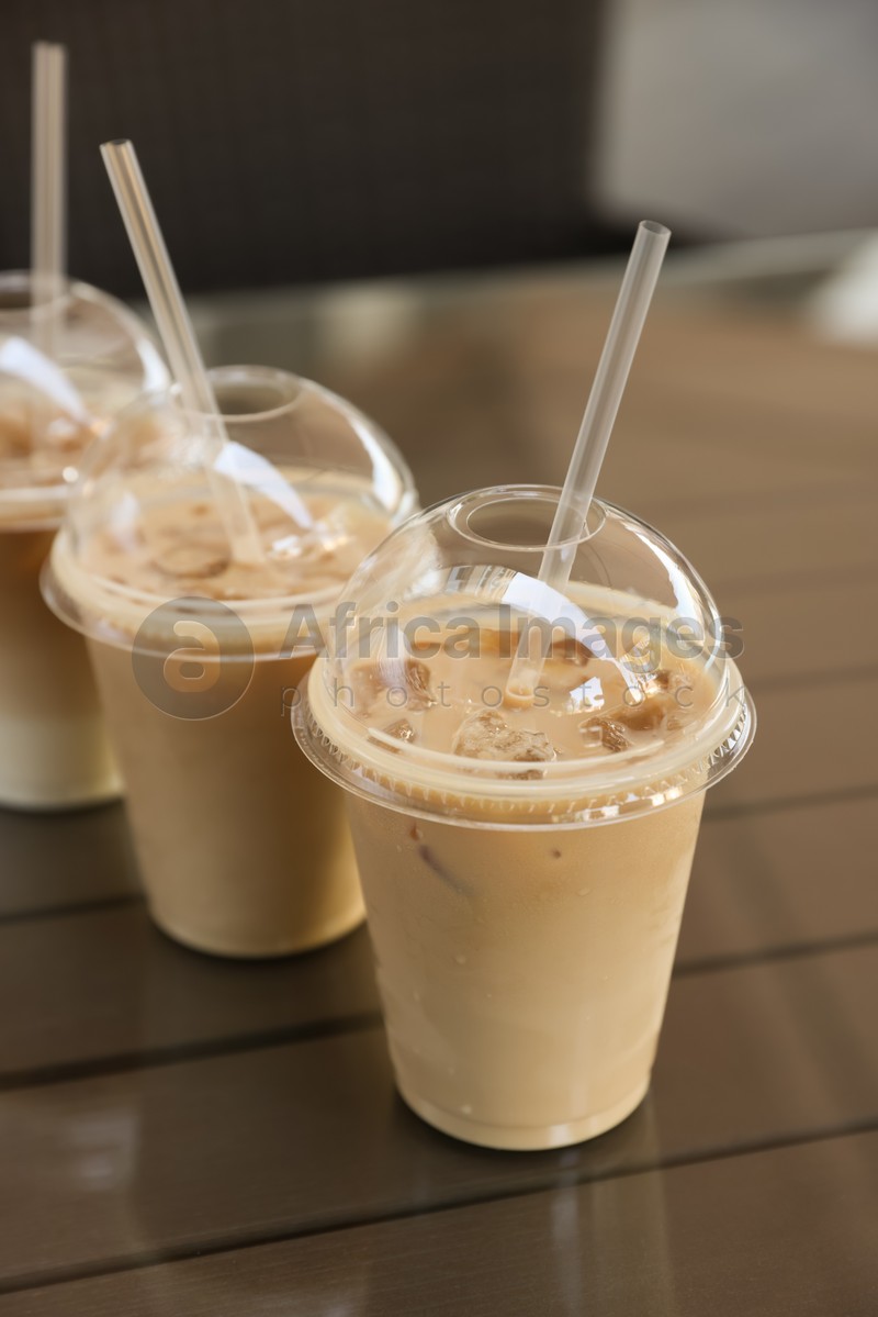 Plastic takeaway cups of delicious iced coffee on table in outdoor cafe