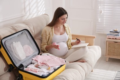 Pregnant woman packing suitcase for maternity hospital at home