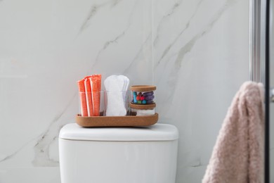 Organizer with different feminine hygiene products on toilet bowl in bathroom
