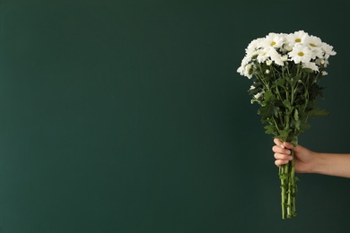 Woman holding beautiful bouquet near green chalkboard, space for text. Happy Teacher's Day