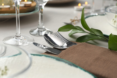 Elegant cutlery with green plant on table, closeup. Festive setting