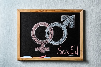 Gender symbols and text "SEX ED" written on small blackboard