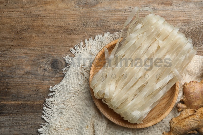 Photo of Rice noodles and ginger on wooden table, flat lay