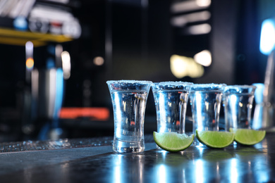 Mexican Tequila shots and lime slices on bar counter. Space for text