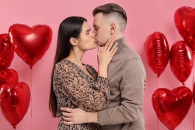 Photo of Lovely couple kissing on pink background. Valentine's day celebration