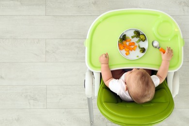 Cute little baby eating healthy food, top view. Space for text