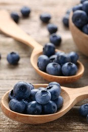 Spoons with tasty fresh blueberries on wooden table, closeup