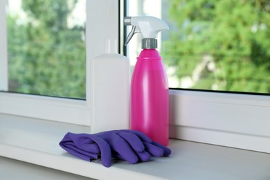 Bottles of detergents and gloves on window sill indoors