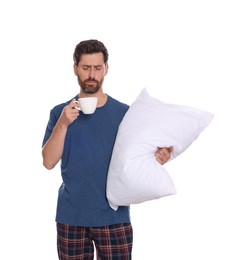Photo of Tired man with cup of drink and soft pillow on white background