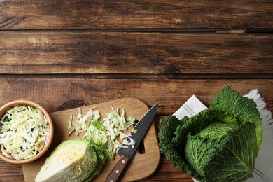Photo of Whole and cut fresh savoy cabbages on wooden table, flat lay. Space for text