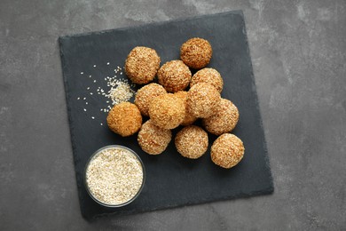 Photo of Delicious sesame balls and seeds on grey table, top view