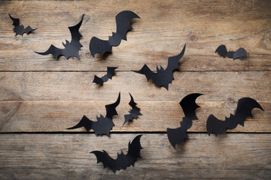 Paper bats on wooden background, flat lay. Halloween decor