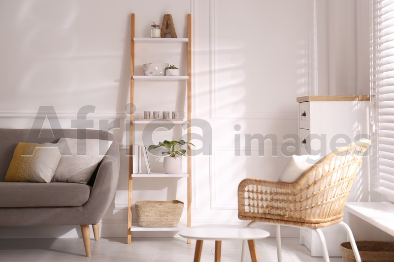Photo of Elegant decorative ladder near sofa in living room