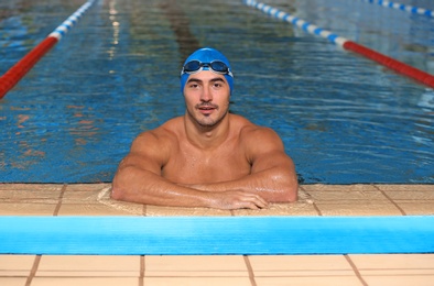 Young athletic man wearing cap and goggles in swimming pool