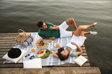 Photo of Happy couple spending time on pier at picnic, above view