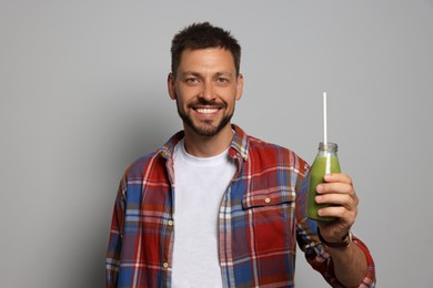 Photo of Happy man holding bottle of delicious juice on grey background