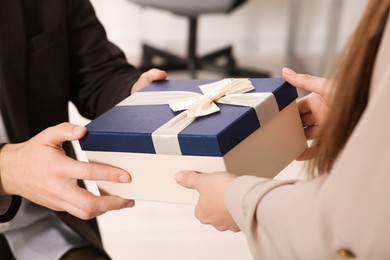 Photo of Woman presenting gift box to his colleague in office, closeup