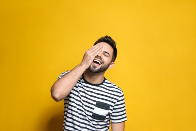 Young man laughing on yellow background. Funny joke