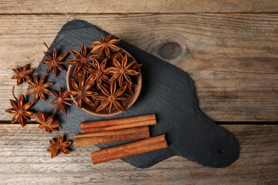 Aromatic cinnamon sticks and anise stars on wooden table, flat lay. Space for text