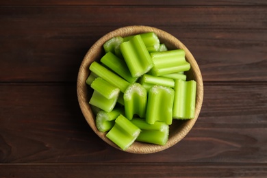 Photo of Cut celery in bowl on wooden table, top view